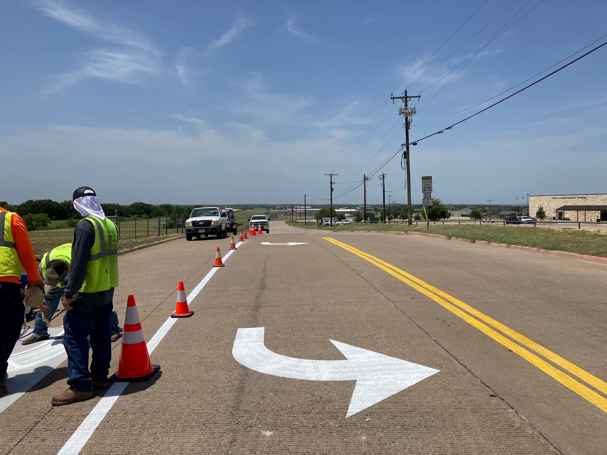 City Street Maintenance workers patching a road near a turning lane.