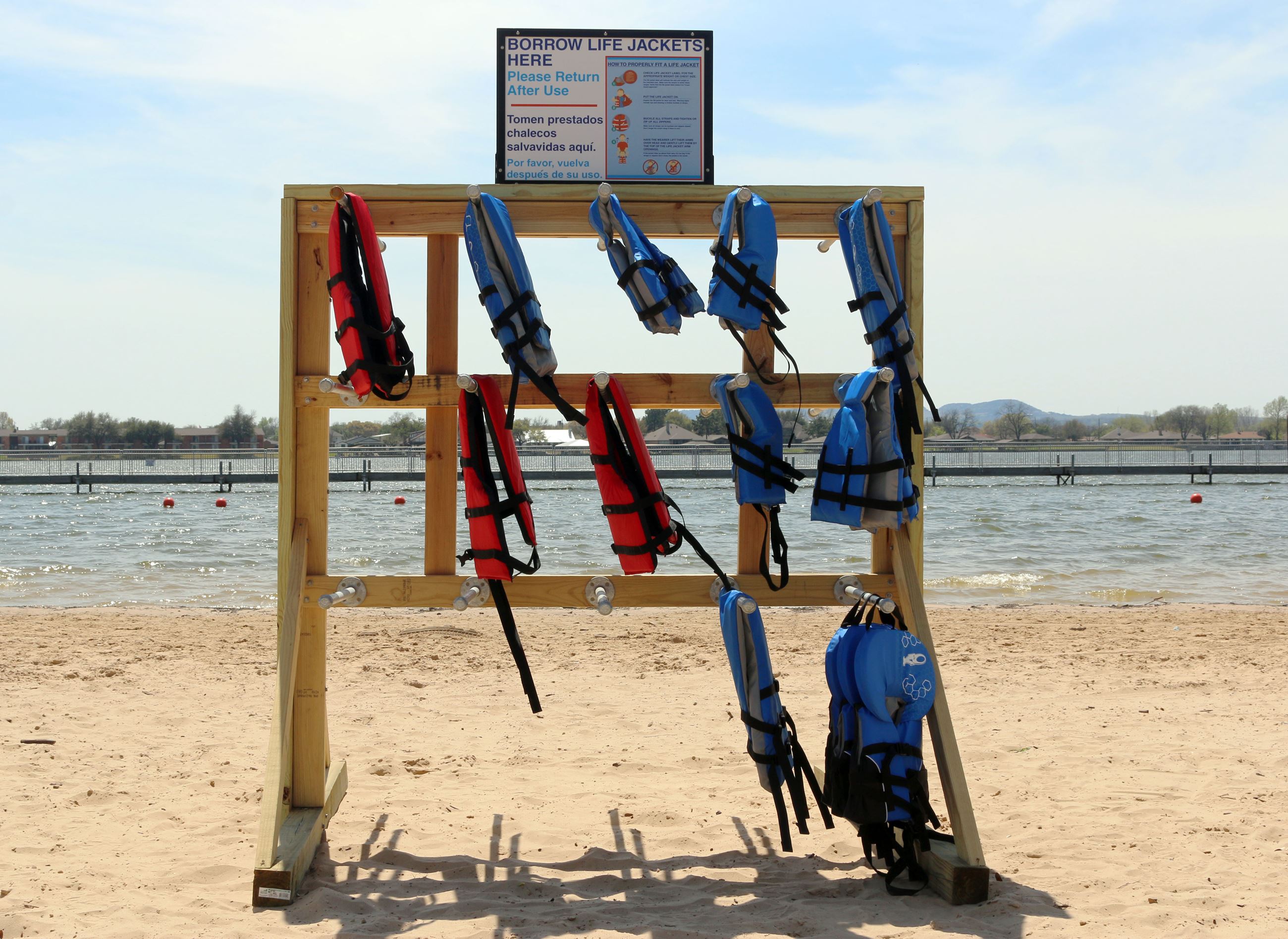 Wooden stand with lifejackets hanging on it on a beach.