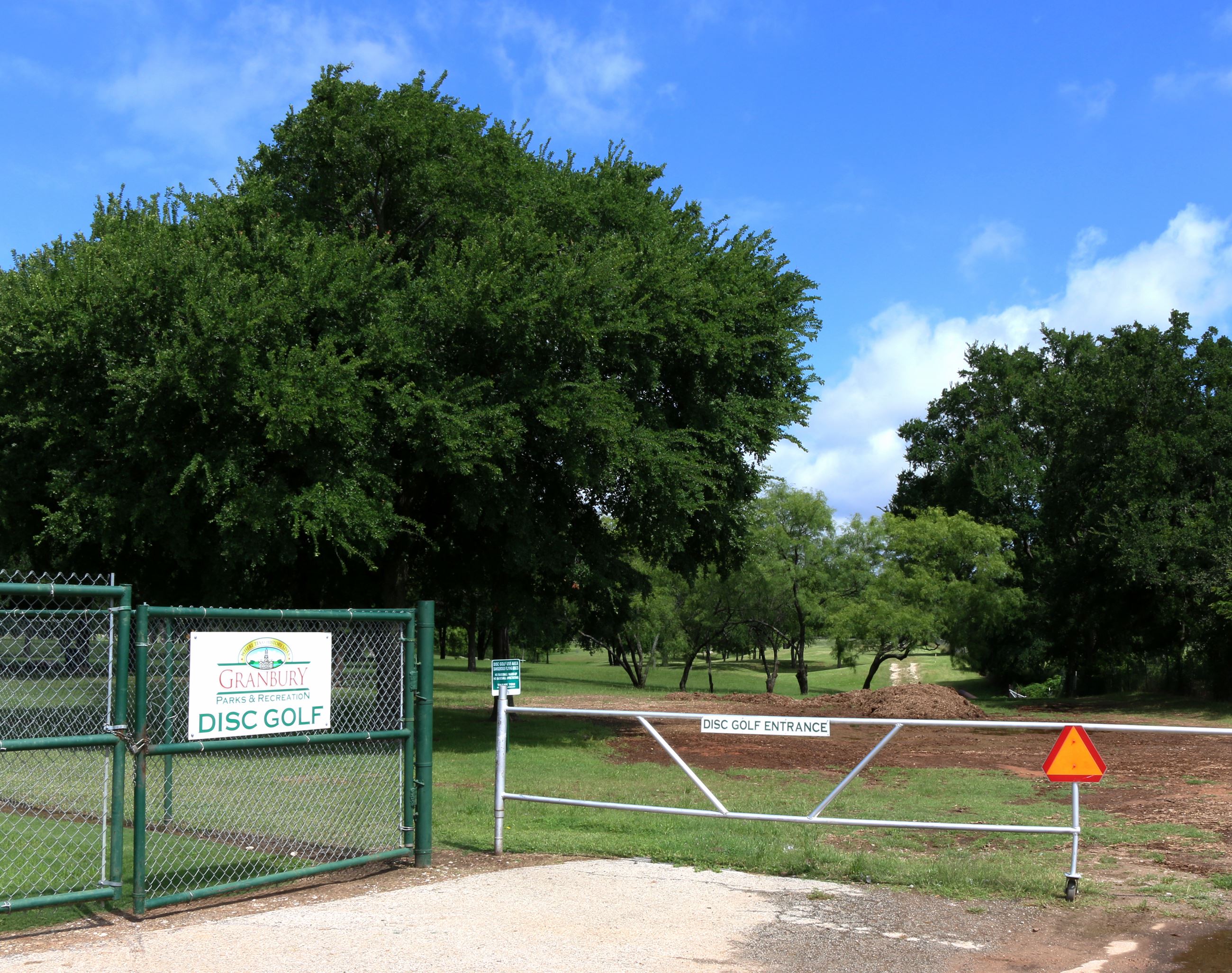 A gate with a City of Granbury Disc Golf sign that leads to the disc golf course.